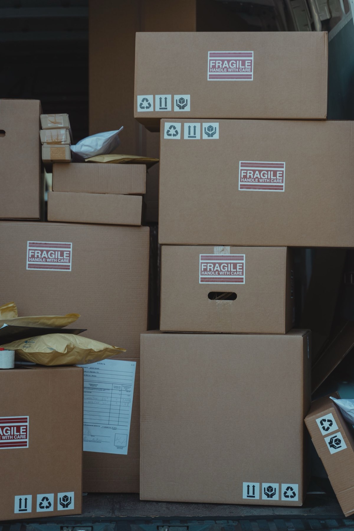A stack of cardboard shipping boxes and padded mailers, several marked Fragile